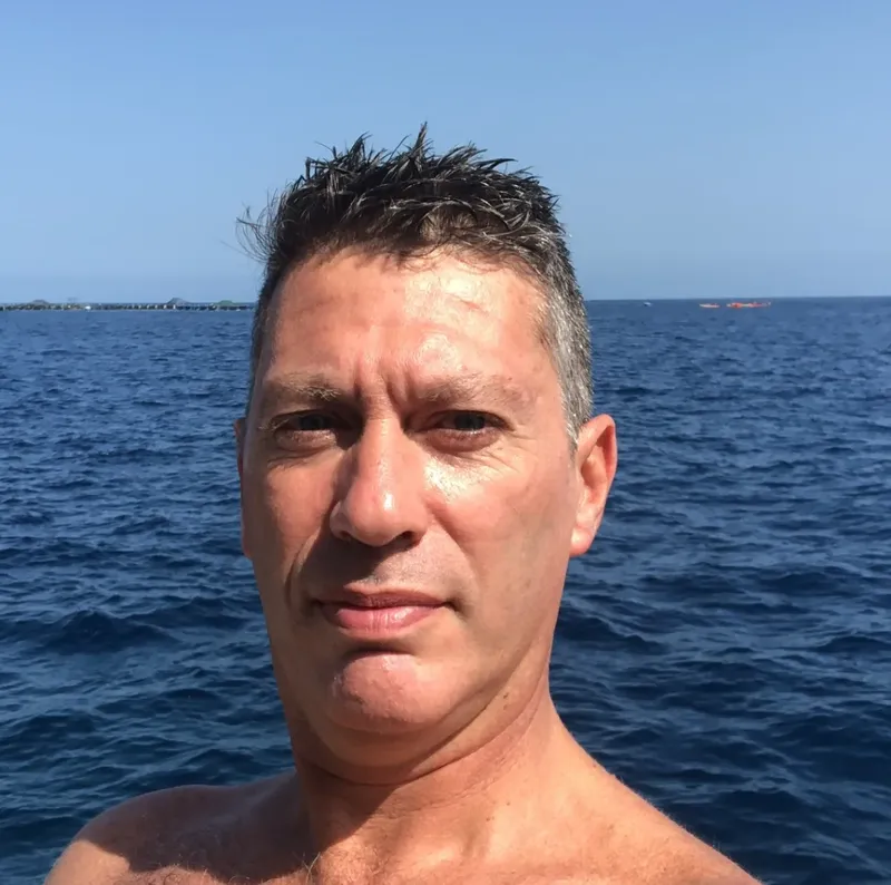 Portrait d'un homme souriant en mer, ciel bleu en arrière-plan