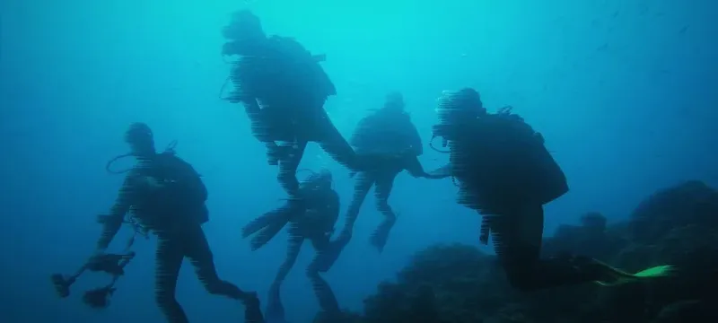Groupe de plongeurs en exploration sous-marine dans une eau bleue
