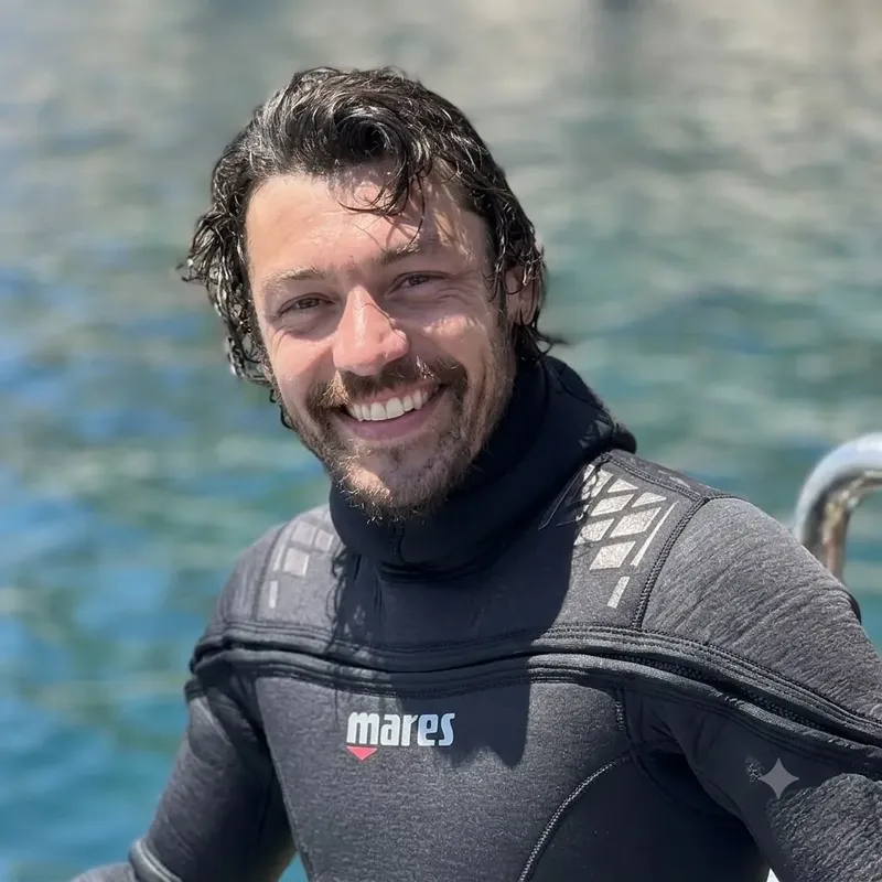 Portrait d'un homme souriant en combinaison de plongée sur un bateau