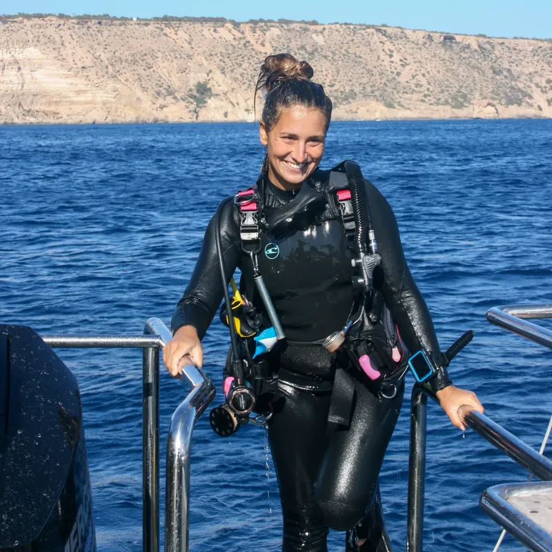 Plongeuse souriante en combinaison complète sur un bateau en mer