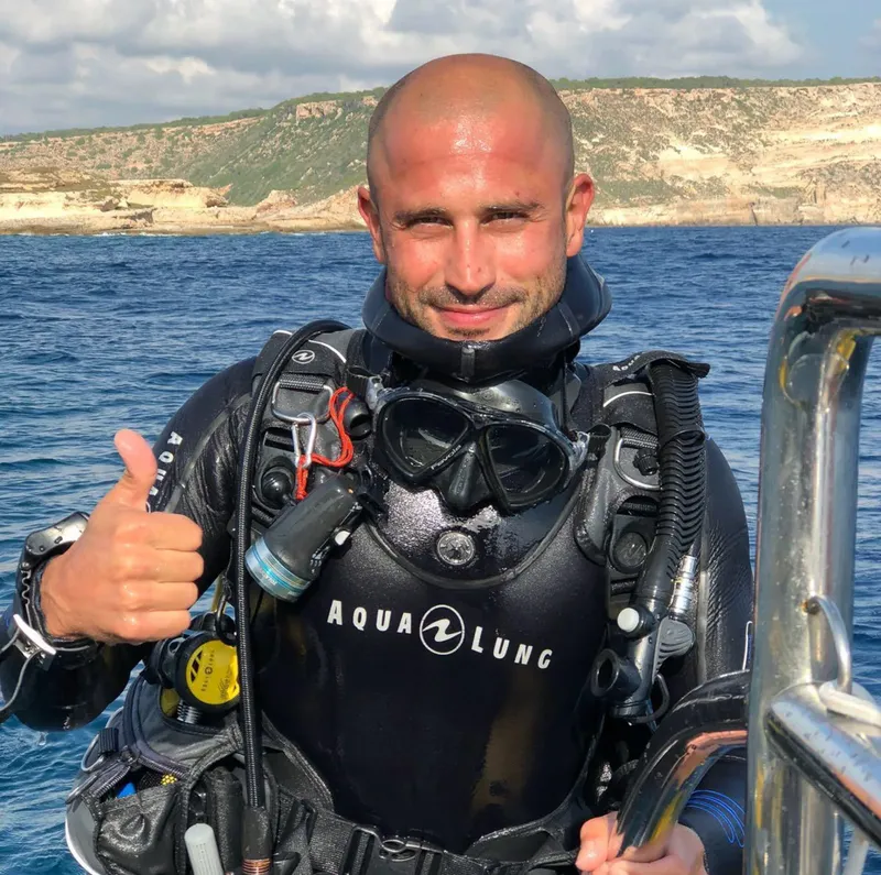 Plongeur souriant avec combinaison et équipement complet, pouce levé