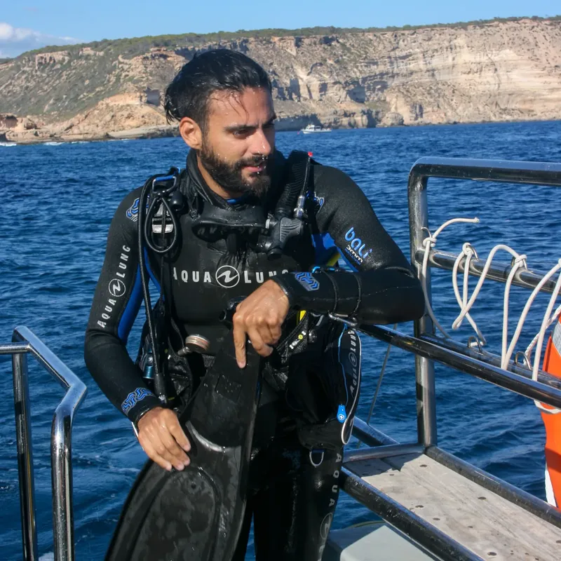 Plongeur équipé sur un bateau, regardant vers l'horizon en mer