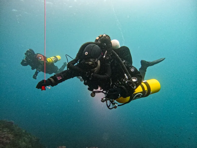 Deux plongeurs en combinaison explorent les profondeurs sous-marines bleues