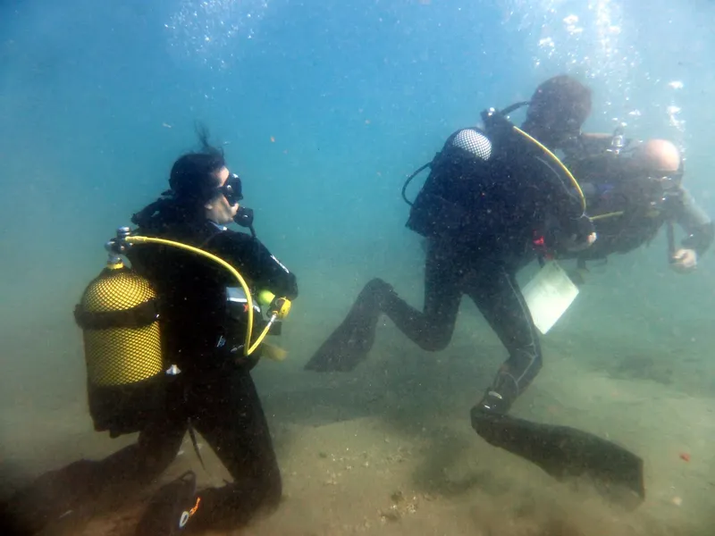 Deux plongeurs en combinaison explorent les fonds marins sablonneux