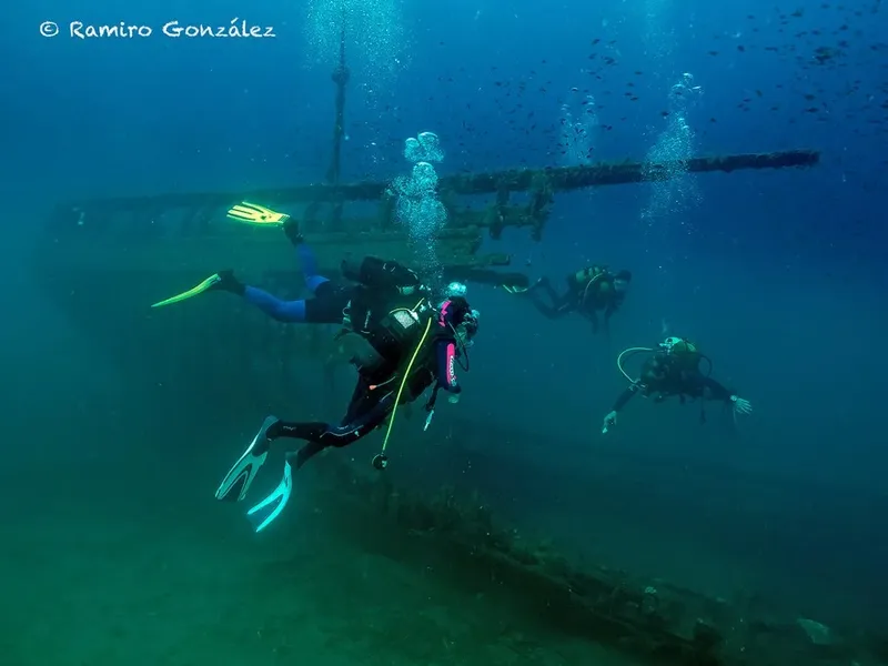 Plongeurs explorent une épave sous-marine avec des bulles et lumière
