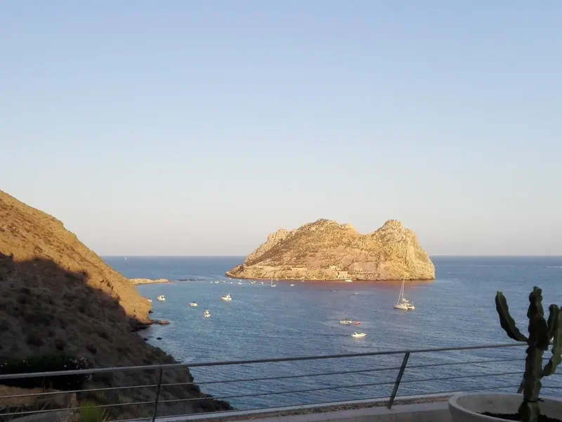 Vue d'une île rocheuse en mer avec des bateaux à voile