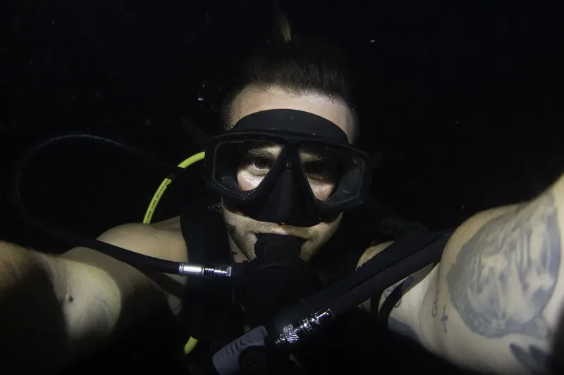Plongeur avec masque et détendeur, regardant la caméra sous l'eau