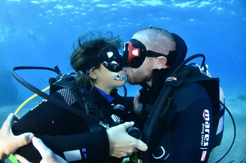 Couple de plongeurs s'embrasse sous l'eau avec équipement complet