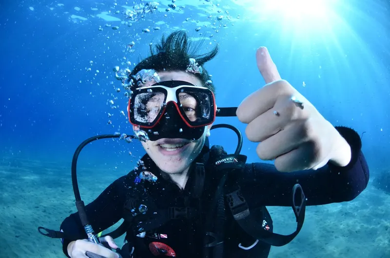 Plongeur souriant avec signe de validation sous l'eau bleue