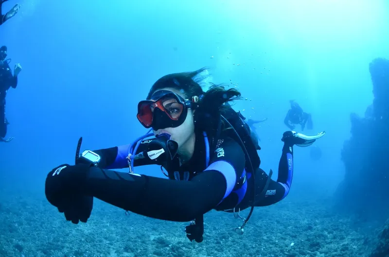 Plongeuse souriante donne un signe OK sous l'eau bleue