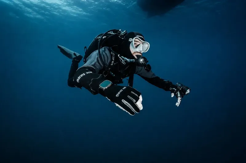 Plongeur en combinaison noire nageant dans une eau bleue profonde