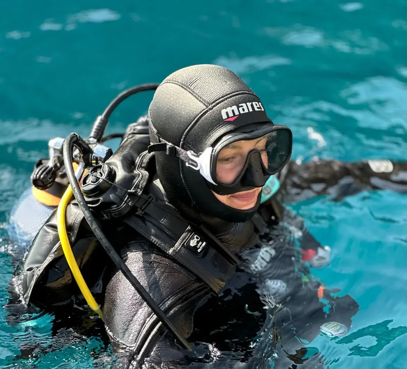 Plongeuse en combinaison noire avec masque et détendeur dans l'eau