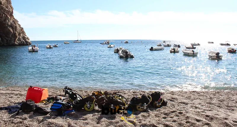Plage avec bateaux amarrés et équipement de plongée sur le sable