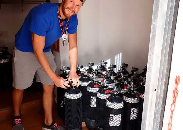 Un homme vérifie une bouteille de plongée dans un local bien rangé