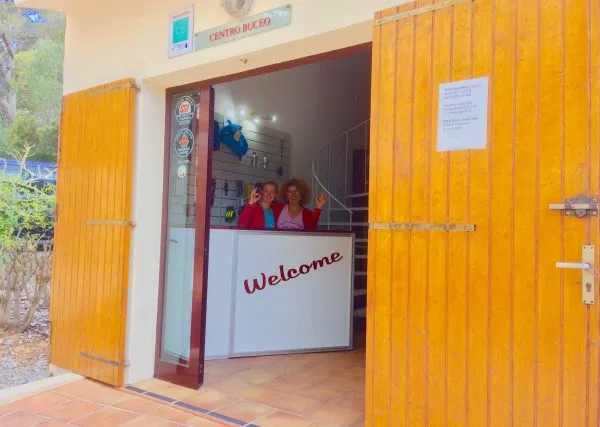 Deux femmes souriantes accueillent devant un comptoir dans un centre