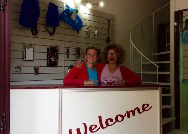 Deux femmes souriantes derrière un comptoir d'accueil avec du matériel