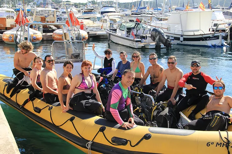 Groupe de plongeurs souriants sur un bateau jaune dans un port