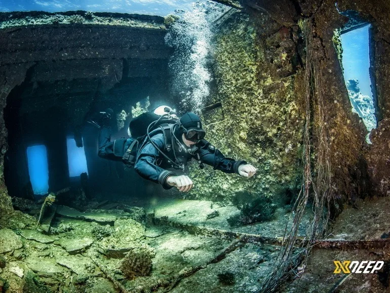 Plongeur explore une épave sous-marine avec lumière et particules
