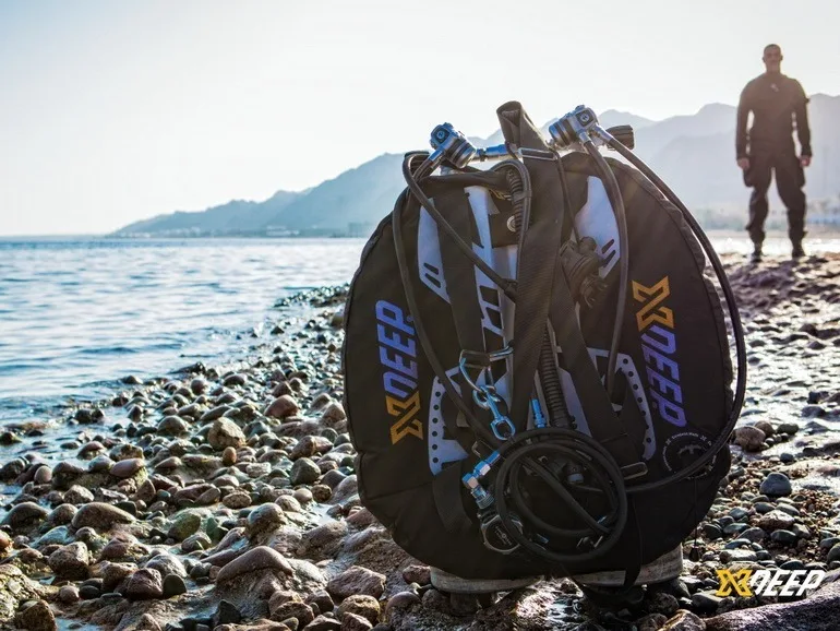 Equipement de plongée sur plage de galets, un plongeur se prépare