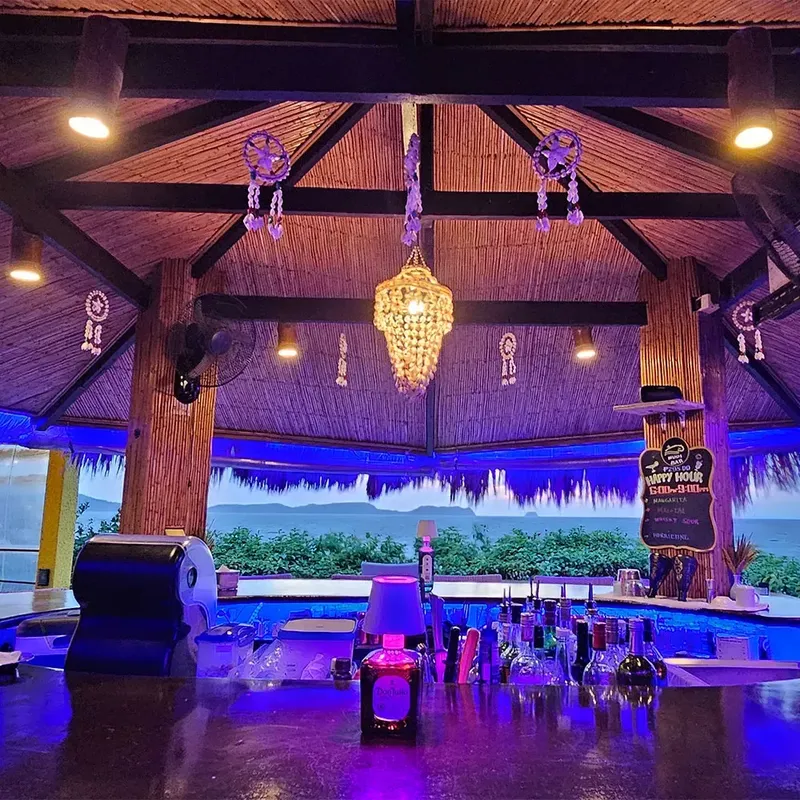 Bar éclairé en bleu avec comptoir, bouteilles et menu happy hour