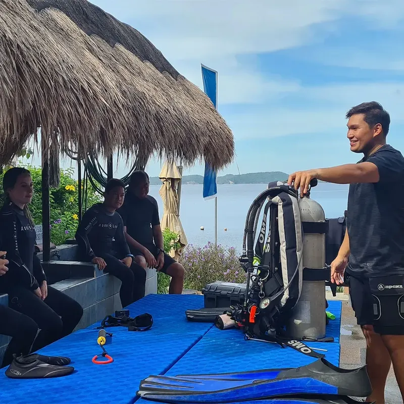 Plongeurs préparant leur matériel sur une terrasse ensoleillée face à la mer