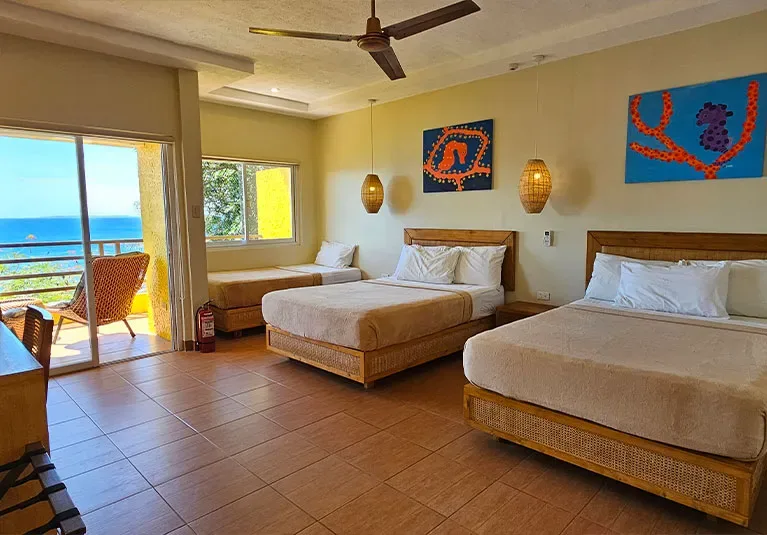 Chambre spacieuse avec vue sur la mer, lits et décoration tropicale