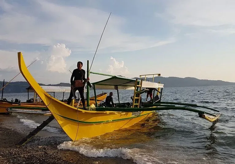 Bateau de pêche jaune avec des personnes à bord sur l'eau