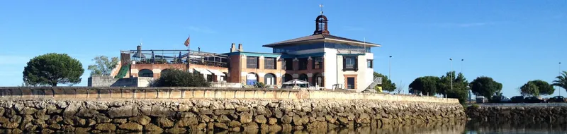 Bâtiment coloré au bord de l'eau avec quai en pierre et ciel bleu