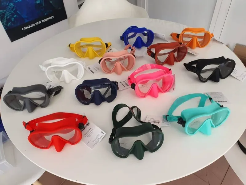 Masques de plongée de différentes couleurs disposés sur une table blanche