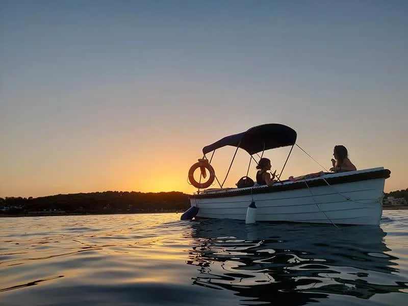 Trois personnes à bord d'un bateau au coucher du soleil