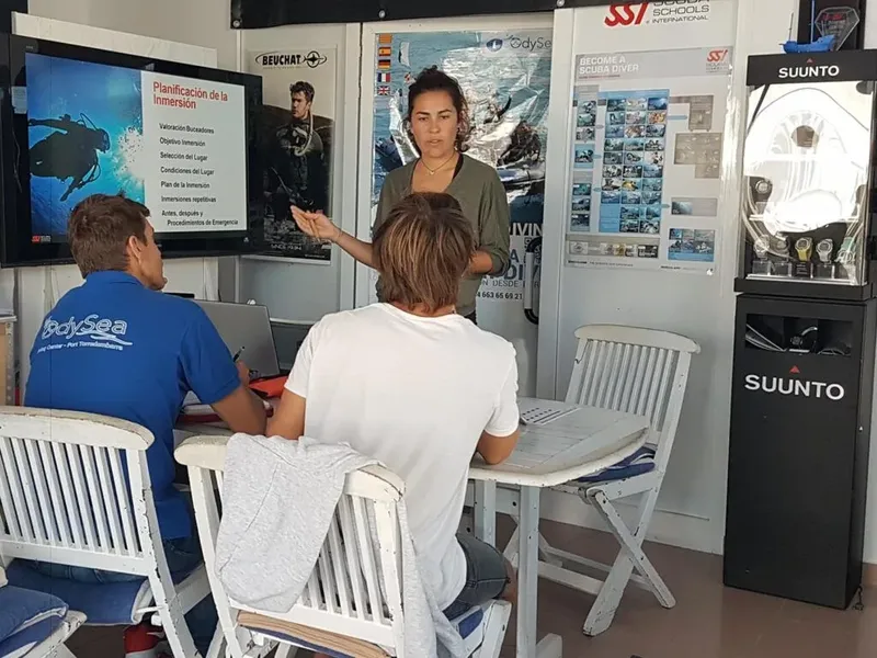 Cours de plongée en intérieur avec instructrice et participants attentifs