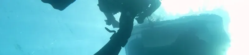 Vue sous-marine d'une coque de bateau et d'un plongeur remontant