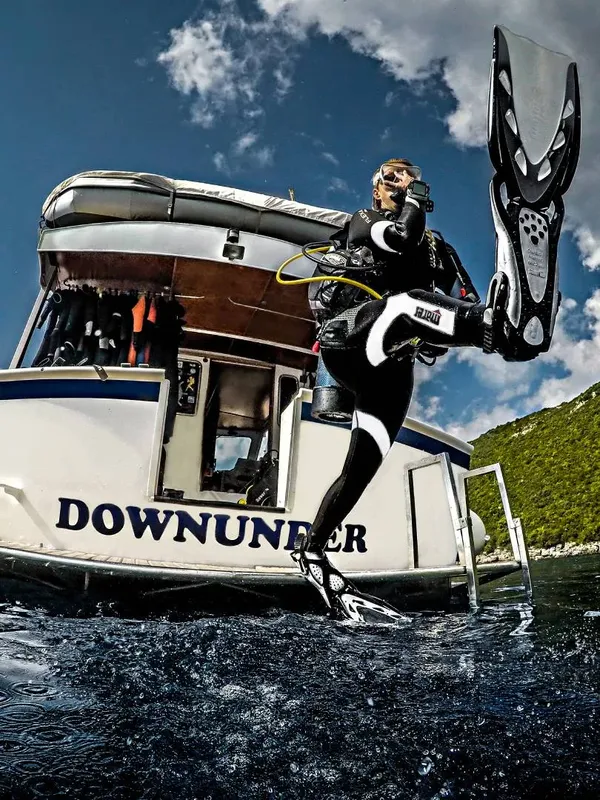 Plongeur s'equipant sur un bateau de plongée avec palmes et masque