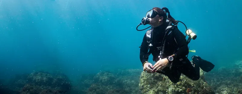 Plongeuse en combinaison noire explore les fonds marins bleus