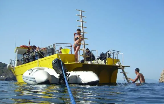 Bateau de plongée jaune avec des plongeurs se préparant à entrer dans l'eau