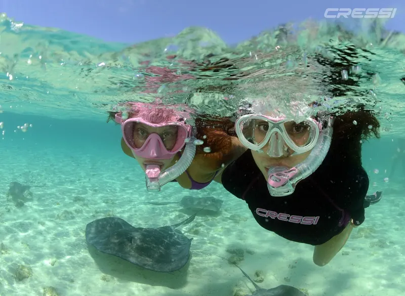 Deux plongeuses souriantes avec masque et tuba dans l'eau turquoise
