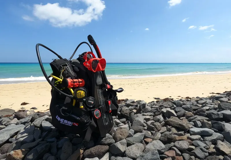 Equipement de plongée complet posé sur des galets face à la mer