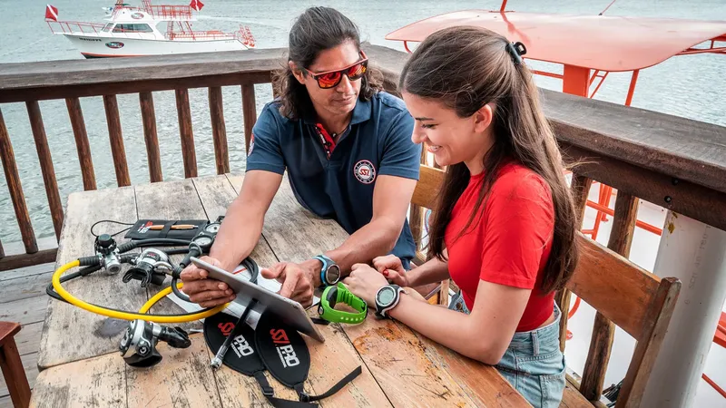 Instructeur et élève regardent une tablette avec du matériel de plongée