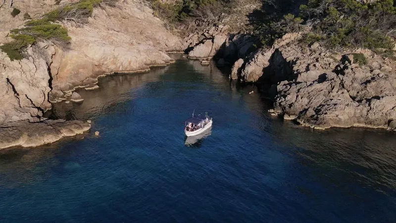 Bateau de plongée navigue entre deux falaises rocheuses dans une crique