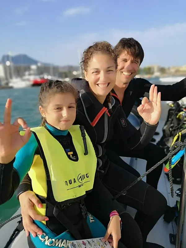 Trois personnes souriantes sur un bateau, portant des gilets de sauvetage