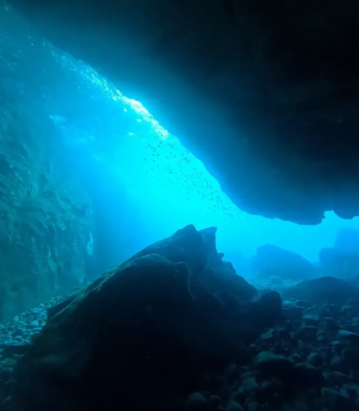 Vue sous-marine d'une grotte rocheuse avec des rayons de lumière