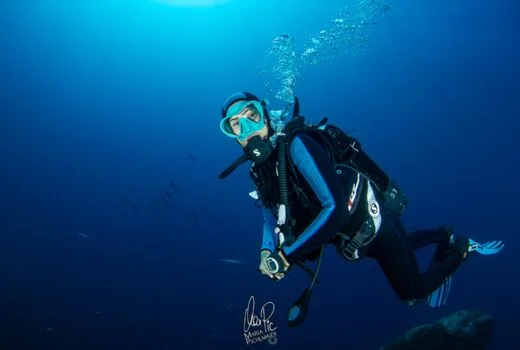Plongeuse souriante en combinaison, explorant les profondeurs bleues de l'océan