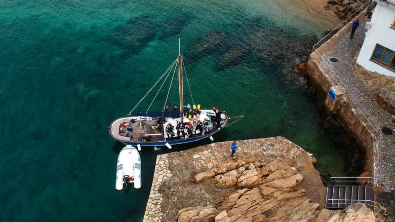 Bateau de plongée amarré avec des plongeurs équipés près du rivage
