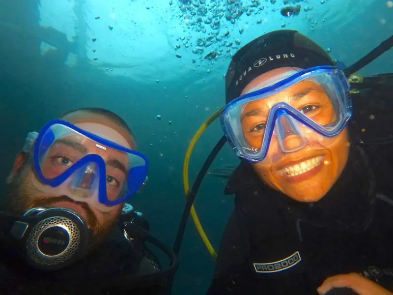 Deux plongeurs souriants, masques et détendeurs, dans une eau bleue