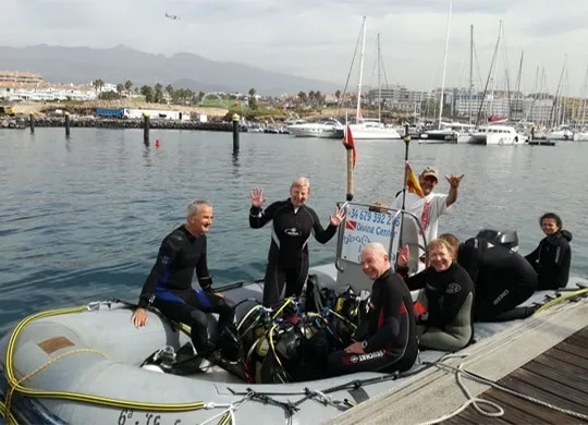 Groupe de plongeurs souriants sur un bateau pneumatique au port