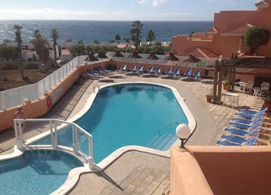 Piscine d'un complexe hôtelier avec transats et vue sur la mer