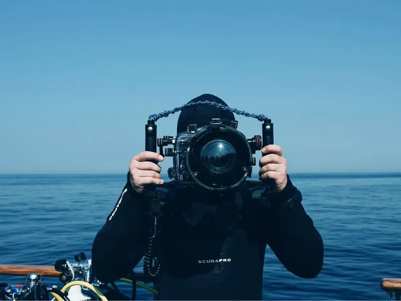 Plongeur avec un appareil photo sous-marin face à l'océan bleu