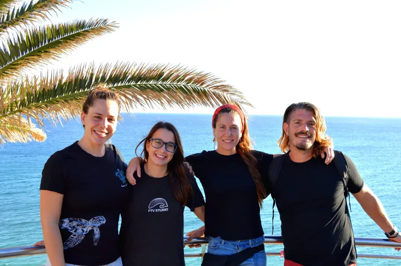 Quatre personnes souriantes posent ensemble devant la mer et le ciel bleu