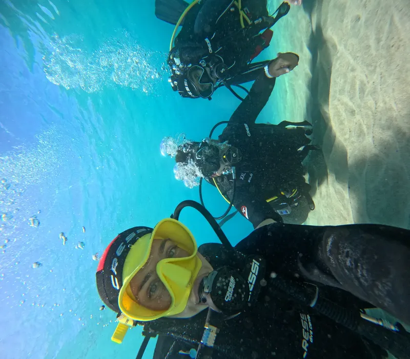 Plongeurs sous l'eau avec équipement complet, visibilité claire et sable