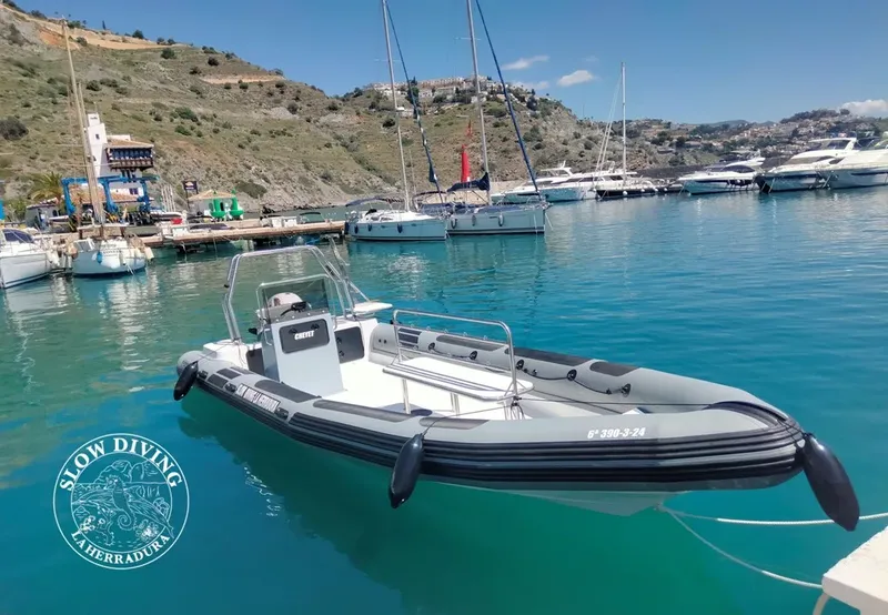 Bateau semi-rigide amarré dans une baie avec des plongeurs en arrière-plan